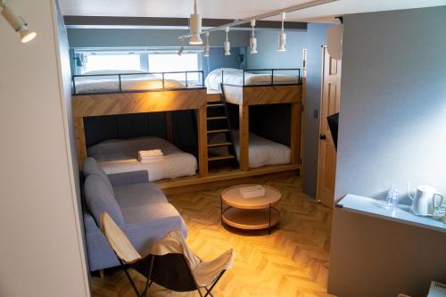 a room with bunk beds with a couch and a table at HOTEL ORIGO HAKATA - Gion - in Fukuoka