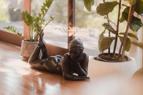 a bronze statue of a woman laying on a table next to potted plants at Runawaytomaleny in Maleny