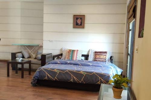 マネサールにあるPremium Apartment in Tarudhan Valley Golf Resortのベッドルーム1室(ベッド1台、椅子、テーブル付)