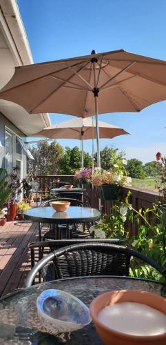 a patio with tables and chairs and an umbrella at Brook House B&B & Cottages in Kaikoura