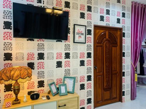 a living room with a tv on a tiled wall at Iris Homestay in Ban Muang
