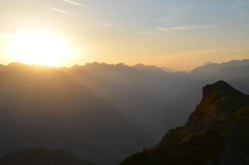 a sunset over a mountain range with the sun setting at Hochjochstöbli B&B Alpine Easy Stay in Schruns-Tschagguns