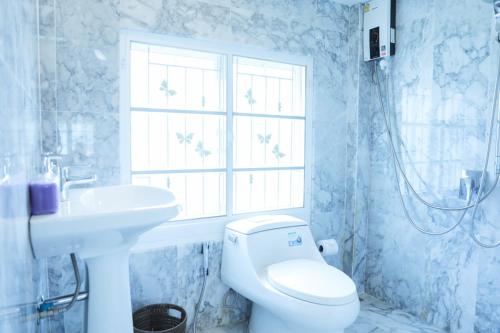 a bathroom with a toilet and a sink and a window at Iris Homestay in Ban Muang