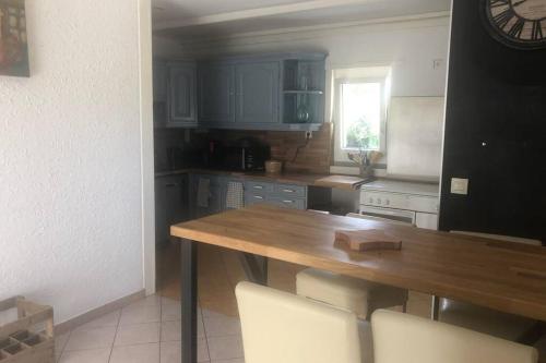 - une cuisine avec une table en bois et des chaises blanches dans l'établissement Maison au pied des dunes, 200m de la plage, à Montmartin-sur-Mer
