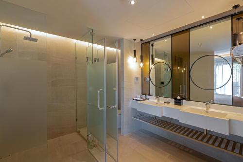a bathroom with two sinks and a glass shower at The Nature Phuket - SHA Extra Plus in Patong Beach