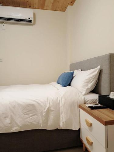 a bedroom with a white bed with a nightstand and avertisement at East Mountain Light Brigade in Nangan