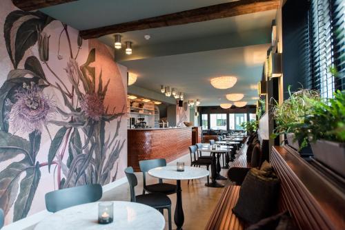 a restaurant with tables and chairs and a flower mural at Zee van Tijd Holwerd in Holwerd