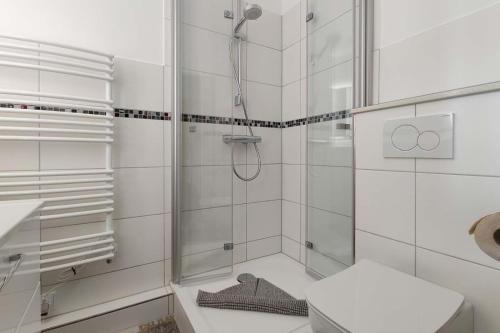 een witte badkamer met een douche en een toilet bij Strandhochhaus-Doese-Ferienwohnung-42-SH42 in Cuxhaven