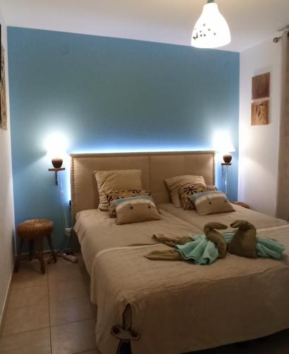 une chambre avec un grand lit avec un mur bleu dans l'établissement Maison Bouzigues, à Bouzigues