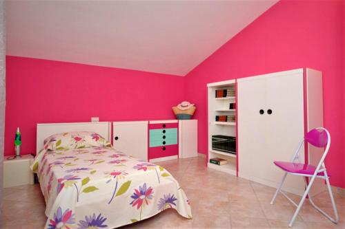 a pink bedroom with a bed and a pink wall at Villa Sophia in Chiesa Nuova