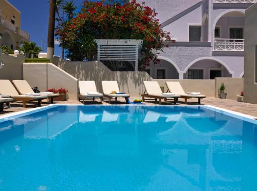 a swimming pool with lounge chairs and a house at Studios Marios in Kamari