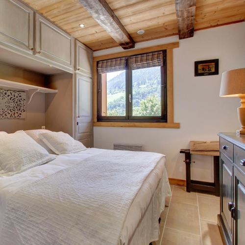une chambre avec un grand lit et une fenêtre dans l'établissement L'Ours Blanc Lodge, à Le Biot