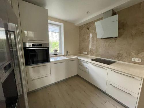 a kitchen with white cabinets and a black microwave at Park-Hotel Tihiy Les in Prokhorovka