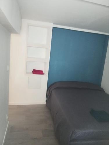 une chambre avec un lit et un mur bleu dans l'établissement Studio aménagé en sous sol, à Arcachon