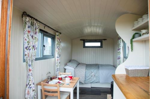 Una habitación con una mesa y una cama en una caravana en Hunstanton Glamping, en Heacham