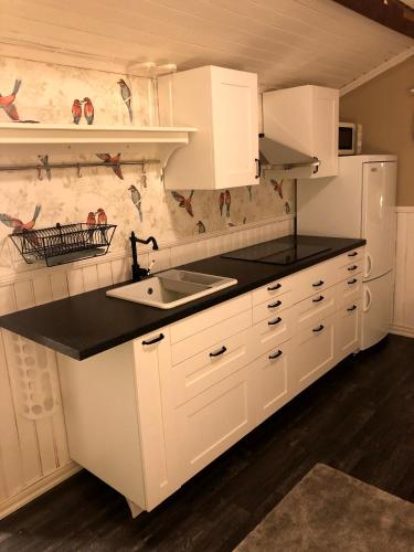 a kitchen with white cabinets and a black counter top at Natursköna Gysinge in Österfärnebo