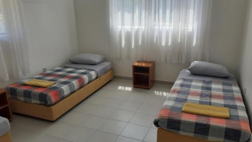 a bedroom with two beds and a table and a window at Apartman PETI PUK in Valjevo