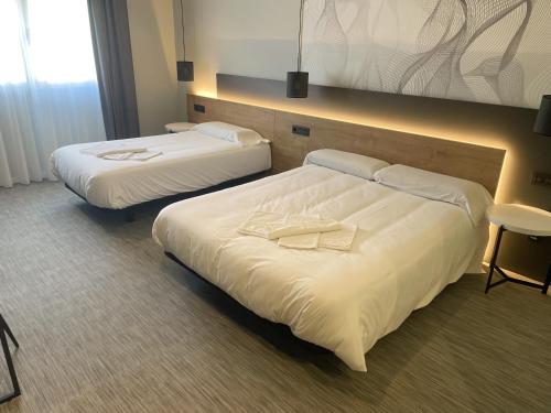 2 camas en una habitación de hotel con sábanas blancas en Area 507, en Outeiro de Rei