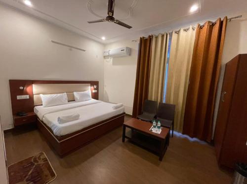 a bedroom with a bed and a table with a chair at Hotel The Shivaay - Delight Inn Rishikesh in Rishīkesh