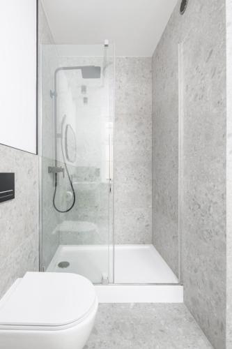 a white bathroom with a shower and a toilet at Apartamenty L11, Limanowskiego in Poznań