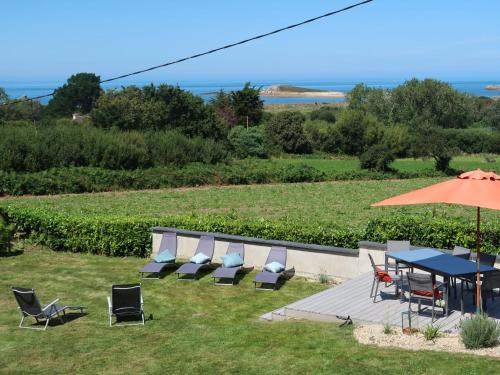 un patio avec des chaises, une table et un parasol dans l'établissement Holiday Home La Rotonde by Interhome, à Port-Blanc