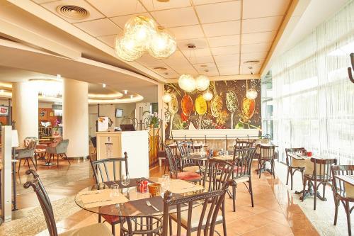 a restaurant with tables and chairs in a room at Continental Forum Bucuresti Palatul Parlamentului in Bucharest