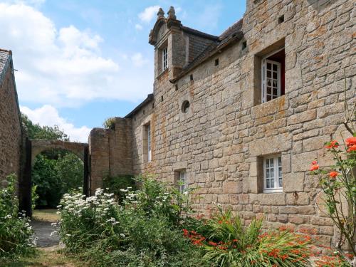 an external view of a stone building with flowers at Holiday Home Le Manoir by Interhome in Pont-lʼAbbé