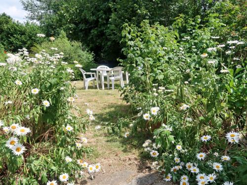 une table et des chaises dans un jardin fleuri dans l'établissement Holiday Home Le Manoir by Interhome, à Pont-lʼAbbé