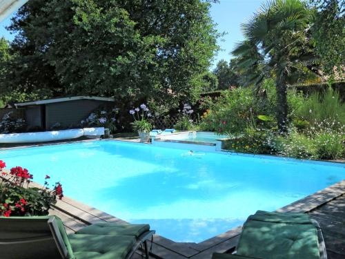 a large blue swimming pool with chairs and flowers at Holiday Home Villa Katy - ADS165 by Interhome in Andernos-les-Bains