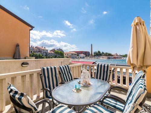 einen Tisch mit Stühlen und einem Sonnenschirm auf dem Balkon in der Unterkunft Apartment Antonella & Napoletano-2 by Interhome in Umag