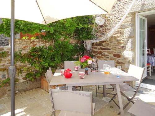 een witte tafel met stoelen en een parasol bij Holiday Home La Pailloussette - A in Cancale