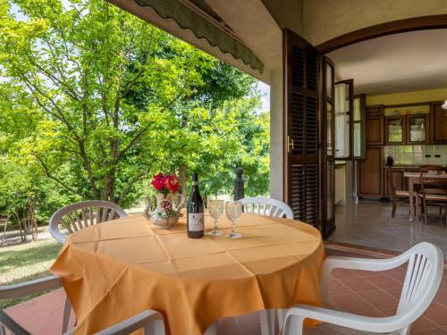 a table with a bottle of wine and flowers on a patio at Holiday Home Culla di Stelle by Interhome in Calosso