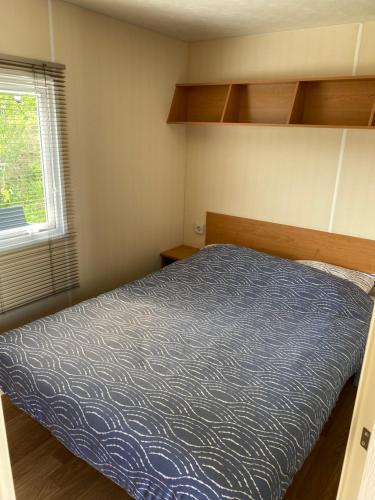 een kleine slaapkamer met een bed en een raam bij Chalet Ibiza in de duinen van IJmuiden aan Zee in IJmuiden