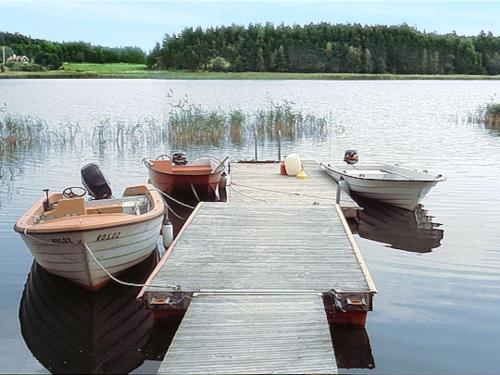 three boats are docked at a dock on a lake at Holiday Home Järnemåla Margaretetorp by Interhome in Valdemarsvik