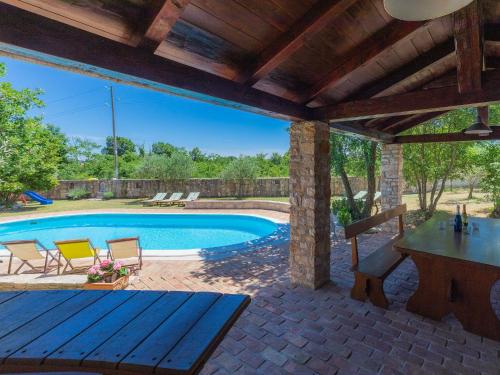 un patio con mesa, sillas y piscina en Villa Elda by Interhome, en Rakalj