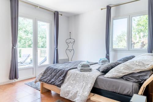 um quarto com uma cama com lençóis cinzentos e janelas em Le Grand Thao em Fréjus