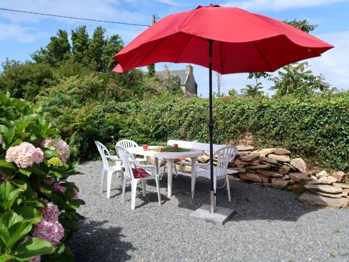 uma mesa e cadeiras sob um guarda-sol vermelho em Holiday Home Ty va Zud by Interhome em Lampaul-Ploudalmézeau