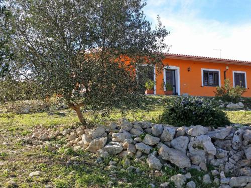 an orange house with a tree and a stone wall at Villa Orange by Interhome in Solarino