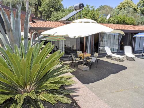 une terrasse avec une table, des chaises et un parasol dans l'établissement Studio Serena by Interhome, à Piedimonte Etneo