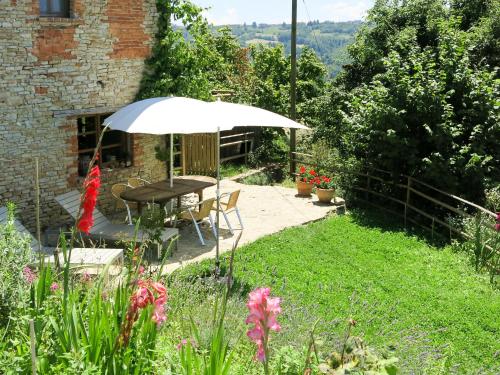 a table and chairs with an umbrella in a garden at Apartment Gallo - MZO103 by Interhome in Belvedere Langhe