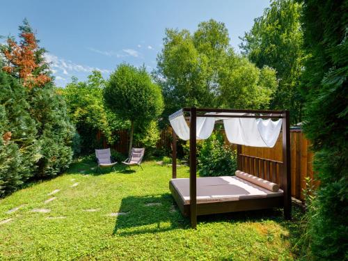 łóżko z baldachimem na podwórzu z dwoma krzesłami w obiekcie Holiday Home Violetta Grande by Interhome w mieście Balatonkenese
