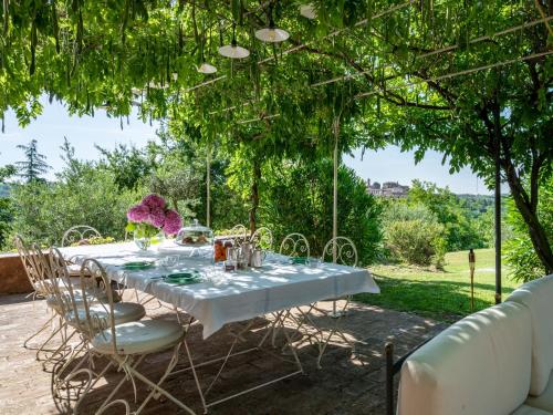 un tavolo con una tovaglia bianca e sedie sotto un albero di Holiday Home Bric del Vento by Interhome a Piea