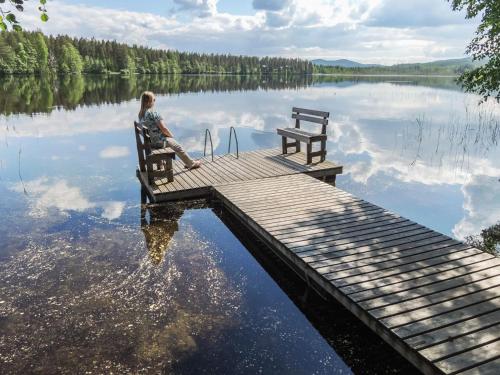 une femme assise sur un banc sur un quai sur un lac dans l'établissement Holiday Home Hiisiranta e4 by Interhome, à Kolinkylä
