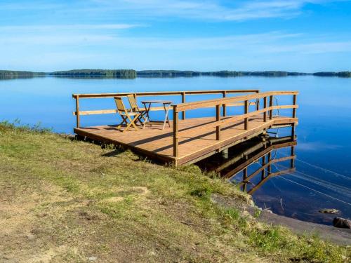 a wooden dock with a table and chairs on the water at Holiday Home Piitterin saunatupa by Interhome in Juuka