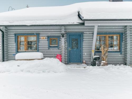 a house with a blue door in the snow at Holiday Home Karhunpesä a by Interhome in Kotila