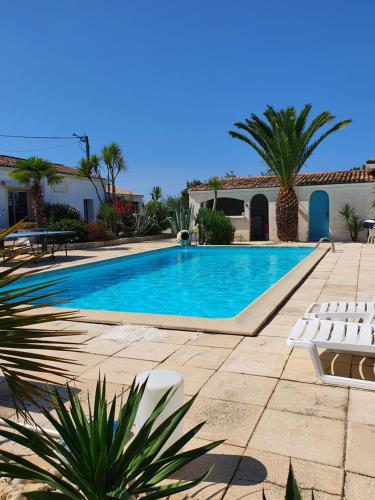 une piscine dans une cour avec des chaises et une maison dans l'établissement VILLA MEDOC OCEAN 2, à Talais