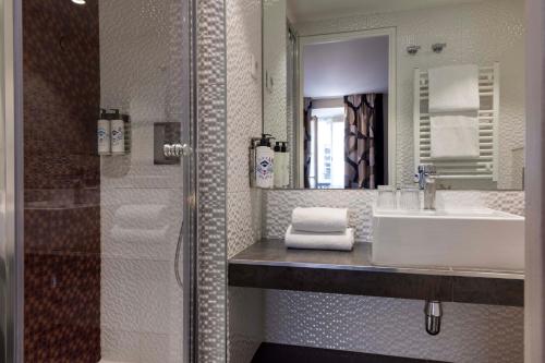 y baño con lavabo, espejo y ducha. en Hôtel Regina Opéra Grands Boulevards, en París