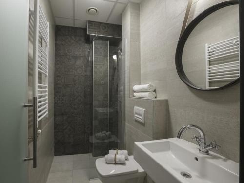 bagno con lavandino, doccia e specchio di Savamala b&b a Belgrado