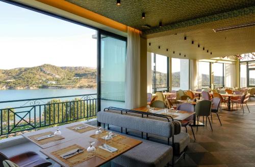 a restaurant with tables and chairs and large windows at Dolce by Wyndham Athens Attica Riviera in Vravrona
