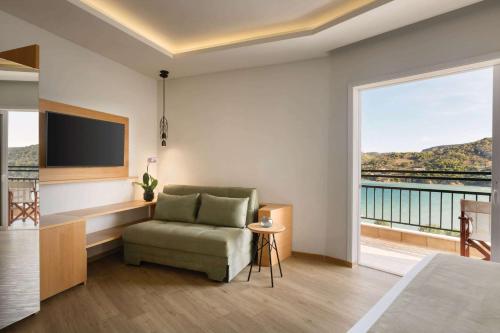 a living room with a chair and a large window at Dolce by Wyndham Athens Attica Riviera in Vravrona